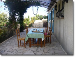 Upper terrace adjoining the villa with a dining table under the pergola